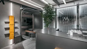 A modern kitchen with a large center island surrounded by chairs, two potted plants, and a focus on functionality and aesthetics