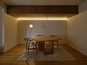A well-lit living area with a wooden dining table and chairs, a couch, and a warm atmosphere