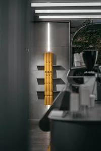A modern interior design showroom with a counter featuring various items, including cups, bowls, and a vase, in a well-organized and well-lit space