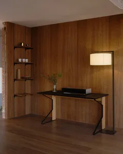 Warm and inviting living area with wooden walls and floors, featuring a table with a vase and a book, and a lamp providing natural light