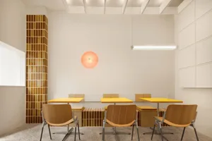 Warm and inviting restaurant interior with wooden tables and chairs in a semi-circle around a central dining area, soft ambient lighting