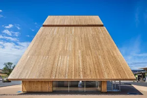 A modern building with a wooden facade, sloping roof, and open interior spaces, featuring minimalistic decoration and an elegant atmosphere