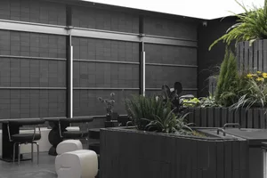 A modern living space with a black wall, large window, potted plants, and chairs, incorporating nature into the interior design