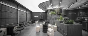 Modern cafe with black and white walls, grey tile flooring, and potted plants, featuring various seating areas and dining tables