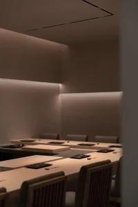 A well-lit conference room with wooden tables and chairs arranged in rows, suitable for business events or gatherings