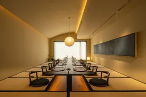 A formal dining area with a long wooden table and chairs, set with wine glasses, suggesting a sophisticated atmosphere