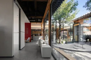 Open living area with wooden floors and walls, featuring a combined kitchen, dining, and living space with furniture and a potted plant