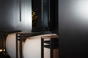 A modern interior space with a large wooden table surrounded by three white vases, suggesting a contemporary home or commercial setting