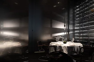 A dining area with a large wooden table and chairs, wine glasses, and an elegant atmosphere