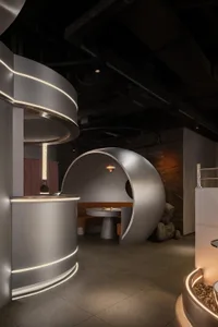 A modern bar area with a circular dining table, grey and silver elements, and a sink serving as a bar counter