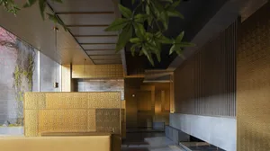 Luxurious hotel lobby with gold walls and ceiling, two benches, and a potted plant, creating a welcoming atmosphere