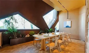A cozy restaurant interior with a large dining table, chairs, potted plants, and various decorative items
