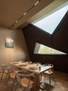 A warm and inviting dining space with a large wooden table surrounded by chairs and decorated with cups, creating a cozy atmosphere