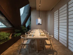 A warm and inviting dining area with a wooden table surrounded by chairs, featuring several cups and a comfortable ambiance