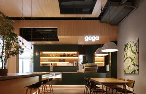 A cozy restaurant dining area with wooden tables, bottles, and comfortable seating for guests