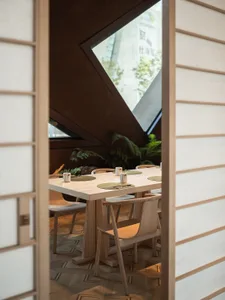 A cozy dining area with a wooden table and chairs, surrounded by cups and utensils, creating an inviting atmosphere