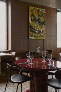 Elegant restaurant dining area with wooden tables, wine glasses, and bottles, set in a comfortable and inviting atmosphere