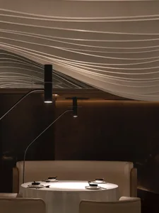 A dining area with a wooden table and chairs, a couch in the background, and multiple cups on the table, creating an elegant and inviting atmosphere