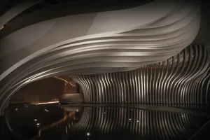A modern interior space with a large white wall featuring a curved wave-shaped structure, creating a sense of depth and interest, with a minimalist atmosphere and clean lines