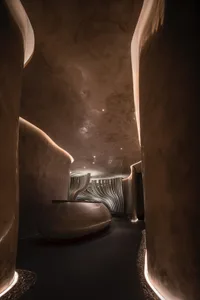 A modern interior space with a large concrete bowl, textured walls, and various lighting fixtures