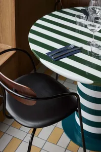 A dining table set with a green and white striped tablecloth, two wine glasses, forks, and a knife, creating an elegant and inviting atmosphere