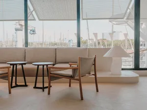 Modern living room with a couch, chairs, dining table, and potted plants, well-lit and inviting
