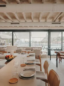Elegant dining space with a wooden table, set with wine glasses, utensils, and candles, creating a warm and inviting atmosphere