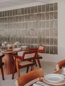 A warm and inviting dining area with a round wooden table surrounded by chairs, wine glasses, and comfortable seating for guests