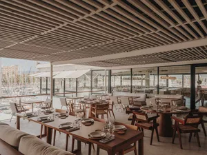 A modern restaurant interior with wooden tables and chairs, well-lit and inviting, with ample seating options