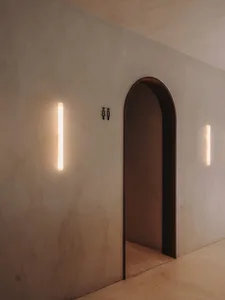 Empty hallway with a wooden doorframe, lit by two lights on either side