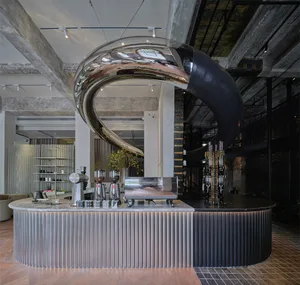 Modern bar area with a counter featuring cups, bottles, and vases, surrounded by potted plants and a stylish atmosphere