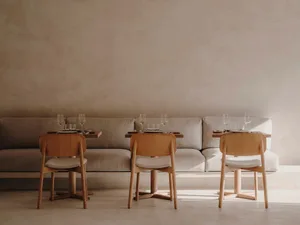 An inviting dining area with a long couch and chairs around a table, wine glasses on the table, and a comfortable atmosphere