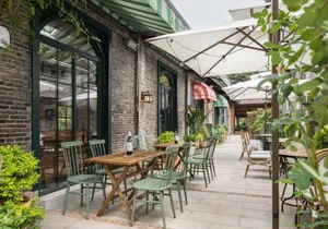 An outdoor dining area with tables, chairs, and umbrellas, set with wine bottles, creating a relaxed and inviting atmosphere