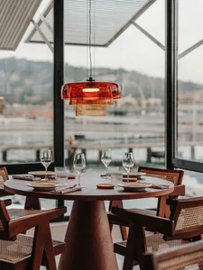 A cozy dining area with a round table surrounded by chairs, wine glasses, and cups, set for a meal or gathering