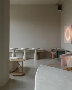Dimly lit contemporary restaurant with a large dining table, chairs, couches, and minimalistic decorations
