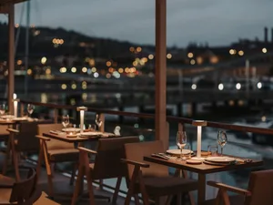 Sophisticated dining space with tables, chairs, wine glasses, and cutlery, featuring a combination of wood and metal elements, warm lighting, and a cozy ambiance