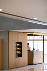 A casual restaurant interior with a counter featuring wooden accents, various items on display, and a person attending to customers