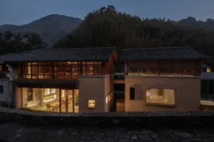 Asian-style house with a large wooden structure, stone roof, and multiple rooms, including a dining area with chairs and potted plants