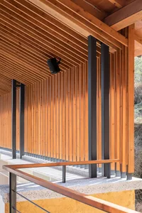 A serene outdoor space with wooden beams and a metal railing, featuring two benches for relaxation and contemplation