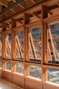 A traditional building with many windows made of wood, set against a stone exterior, with natural light streaming in