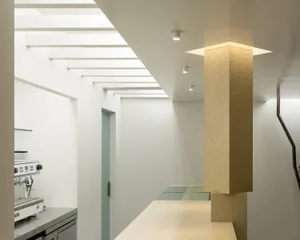 A modern kitchen with two sinks, a white countertop, and marble surfaces, set against a predominantly white background
