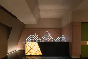 Modern hotel lobby with a diamond-shaped black countertop desk, two chairs, and a sophisticated ambiance