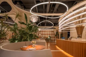 Modern restaurant interior with wooden paneling, tables, chairs, and potted plants, creating a warm and inviting atmosphere