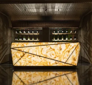 A well-lit bar area with a marble countertop, wine bottles, and a sophisticated atmosphere