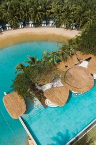 A serene island resort with buildings on stilts over water, surrounded by chairs and a picturesque atmosphere