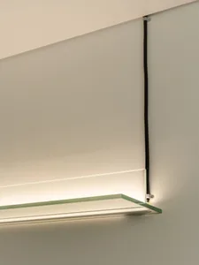 A minimalist interior space with a glass wall and metal frame, well-lit by natural light