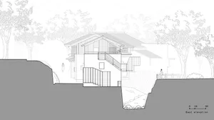 A modern two-story house with a large deck and stairs leading to a lower level, featuring a mix of concrete, wood, and glass materials, with natural light coming through windows