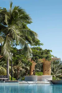 A serene outdoor patio with a wooden structure, surrounded by trees, and two people sitting on a bench enjoying the sunny atmosphere