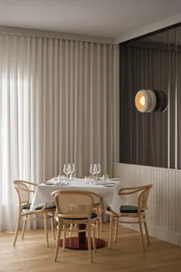 A formal dining area with a large white table surrounded by chairs, wine glasses, and a clean, organized atmosphere