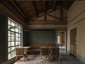 Warm and inviting restaurant interior with wooden floors and walls, multiple dining tables and chairs, and a comfortable atmosphere